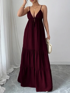 Detail of elegant dark burgundy tiered maxi dress with thin straps and flowing fabric layers