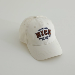 Detailed view of NICE letter embroidery on cream cotton baseball cap for kids