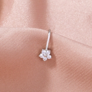 Silver stainless steel flower nose ring with clear diamond studs on pink silk background