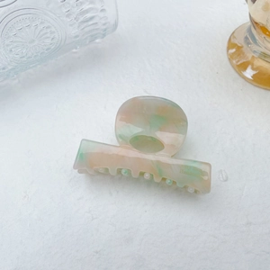 Detail view of pink and green marble pattern acetate hair claw clip with handmade text