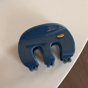 Detail of blue glossy M-shaped hair claw clip with golden Love tag engraved on the side