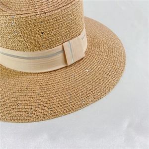 Detail of light brown woven straw sun hat with champagne gold ribbon and silver sequins