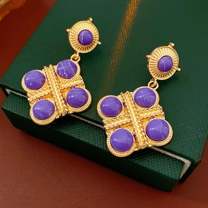 Dettaglio di orecchini vintage dorati con pietra viola su scatola portagioie verde