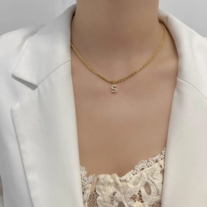 Détail du collier chaîne torsadée dorée avec pendentif lettre S serti de zircons