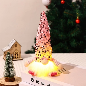 Close-up of a pink sequined glowing Christmas gnome on a book with festive decor