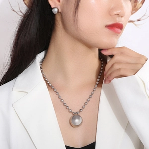 Close-up of model wearing silver hollow ball pendant necklace and matching stud earrings