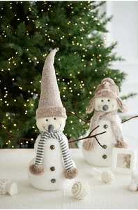 Close-up of plush Christmas snowmen with knitted hats and bells in a cozy festive setting