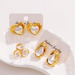 Élégantes boucles d'oreilles dorées 18k avec textures lave et perles blanches sur plateau