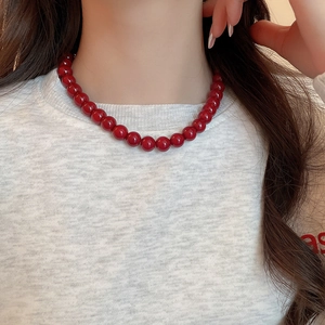 Detail of red glass beaded necklace showing glossy finish and polished round beads