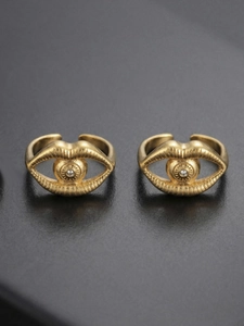 Detail of gold evil eye rings with cubic zirconia inlay on a dark textured background