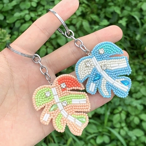 Close-up of handmade beaded monstera leaf keychains with colorful rhinestones and charms