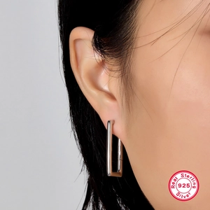 Close-up of minimalist rectangular sterling silver geometric earrings on female ear