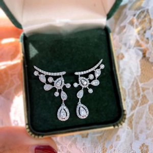 Sparkling pear-cut silver earrings with teardrop tassels on green velvet display