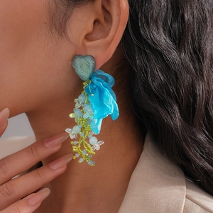 Macro detail of French vintage earrings featuring chiffon fabric flowers and resin heart beads