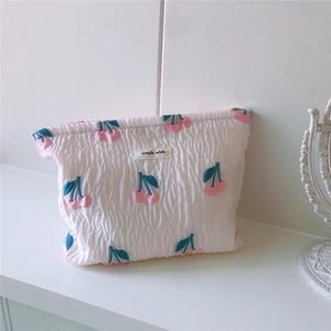Détail de la trousse à maquillage matelassée rose avec broderie cerise et label