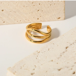 Macro shot of 18K gold plated multi-layer wavy ring on beige travertine stone texture