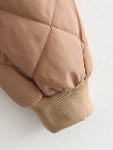 Detailed macro view of khaki quilted bomber jacket featuring ribbed windproof elastic cuffs