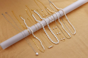 Close-up of pearl necklaces and gold chains layered on white display pedestals