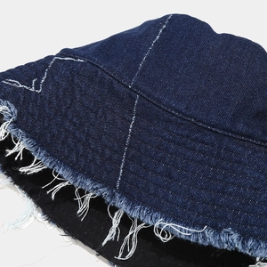 Macro detail of frayed raw edges and contrast stitching on blue denim bucket hat