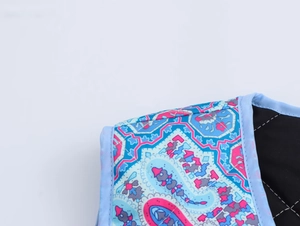 Detail of blue ethnic paisley print fabric with light blue piping and black quilted lining