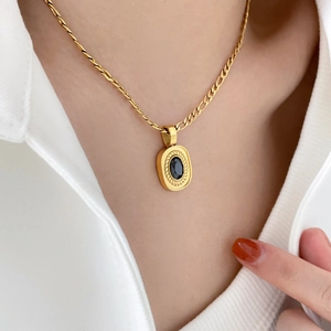Retro gold titanium necklace with oval black gemstone pendant worn on model
