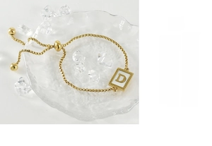 Detailed macro of gold square alphabet D pendant on stainless steel chain with toggle
