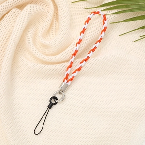Detail of orange and white braided wrist strap with metal clasp on beige fabric