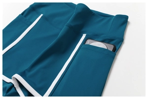 Détail du legging de yoga bleu canard avec poches latérales et liseré blanc contrasté