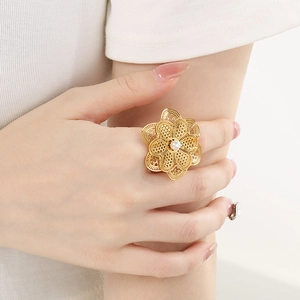 Détail de la bague fleur évidée dorée avec perle blanche sur le doigt d'un mannequin