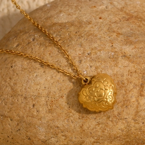 Macro shot of 18K gold plated heart pendant with shell relief on natural stone