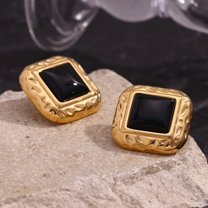 Macro shot of vintage square black acrylic studs with hammered gold-plated finish