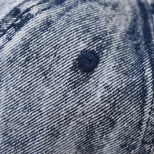 Macro shot of blue washed denim fabric with twill texture and embroidered eyelet detail