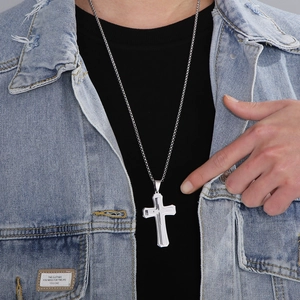 Gros plan d'un collier croix double couche en acier inoxydable porté sur une veste en jean