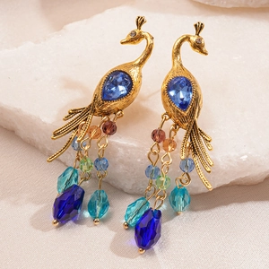 Detailed close-up of golden peacock earrings with blue crystal and multicolor beaded tassels