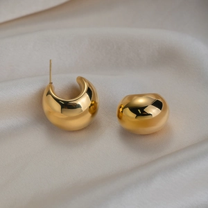 Detail shot of 18K gold plated chunky C-shape hoop earrings on soft white silk fabric