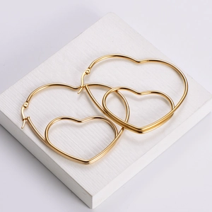 Minimalist golden double heart hoop earrings displayed on white textured block