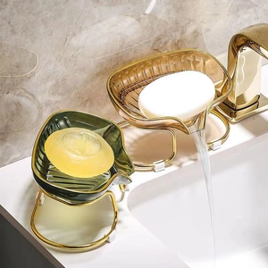Leaf-shaped soap dish with gold metal stand and drainage system on bathroom vanity