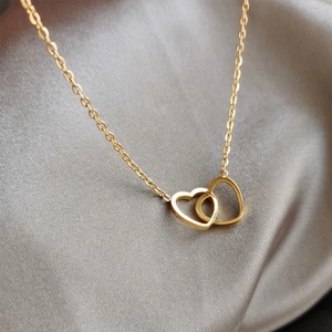 Detail of interlocking double heart pendant in gold finish on elegant silk fabric