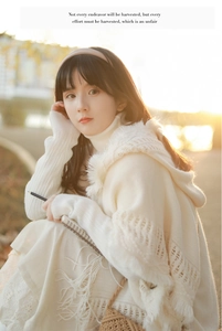 Detail of bohemian knit shawl with fringe and button accents in a soft cream color
