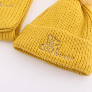 Detail der Strickstruktur von gelbem Kinder-Winterset mit Bären-Stickerei