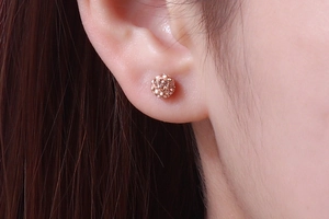 Close-up of a rose gold crystal pave ball stud earring worn on a model's ear
