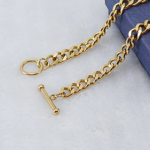 Close-up of golden Cuban link chain featuring an OT toggle clasp on white plush background