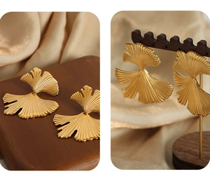 Detail of gold ginkgo leaf earrings featuring intricate textures on champagne silk