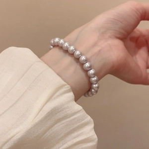 Elegant purple pearl bracelet worn on wrist with textured cream fabric background