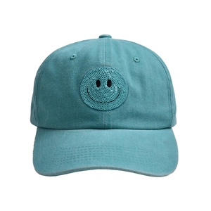 Detail of teal washed cotton baseball cap featuring a sequined smiley face patch