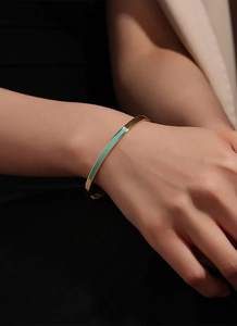 Close-up of a gold minimalist cuff bracelet featuring turquoise enamel inlays on wrist