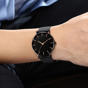 Minimalist men's quartz watch with black dial and Milanese mesh steel strap on wrist