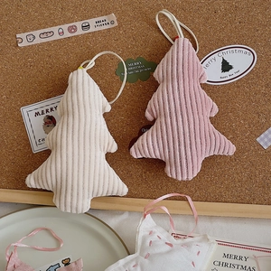 Pink and white corduroy Christmas tree ornaments on cork board with festive stickers
