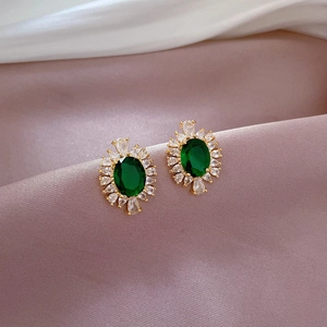 Detailed macro view of vintage gold stud earrings with green stones on silk fabric