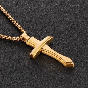 Détail d'un pendentif croix dorée en acier inoxydable avec une chaîne à mailles